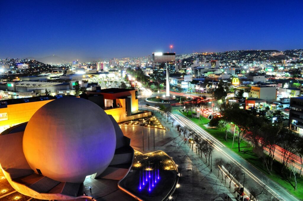 An impressive night view of Tijuana cityscape featuring vibrant lights, architecture, and monument.